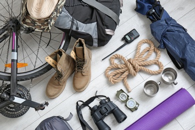 Photo of Flat lay composition with sleeping bag, bicycle and camping equipment on wooden background