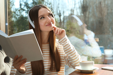 Photo of Woman listening to audiobook at table in cafe