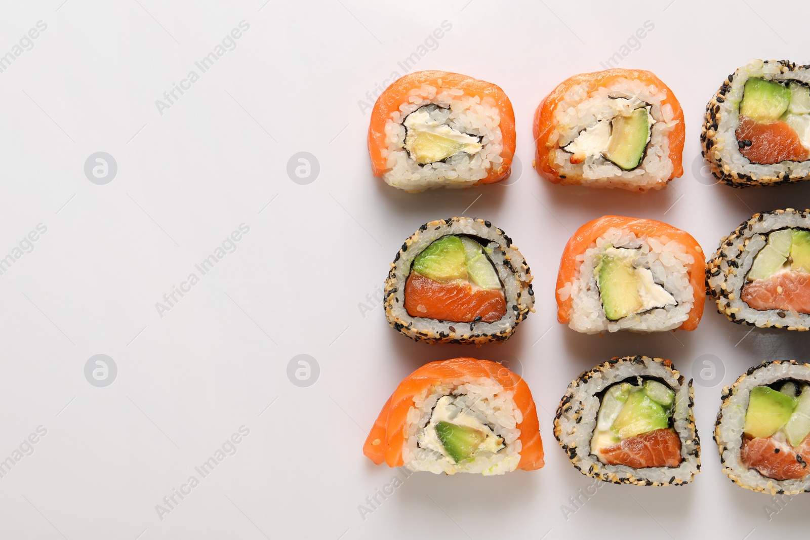 Photo of Delicious sushi rolls on white background, flat lay. Space for text