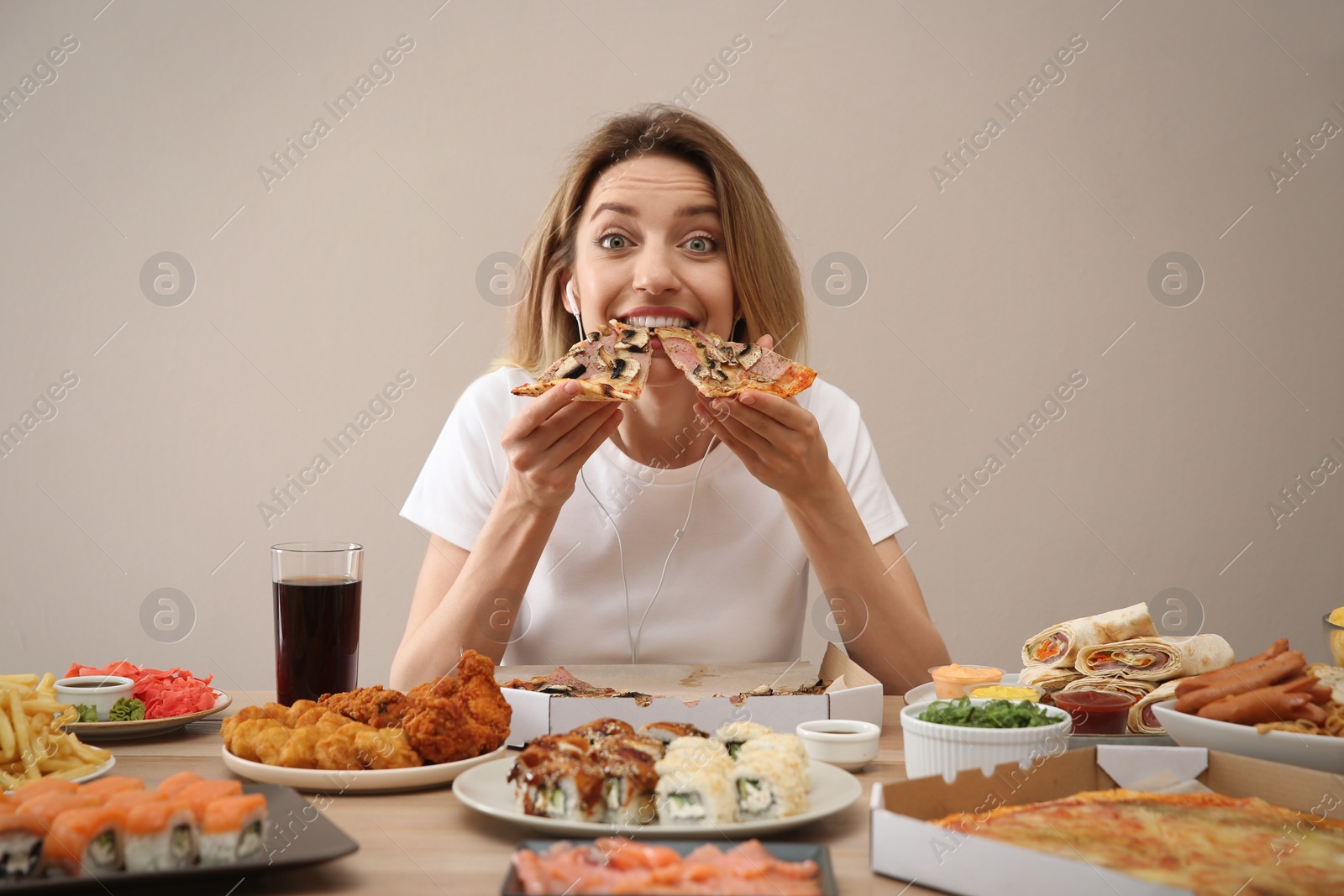 Photo of Food blogger eating at table against beige background. Mukbang vlog