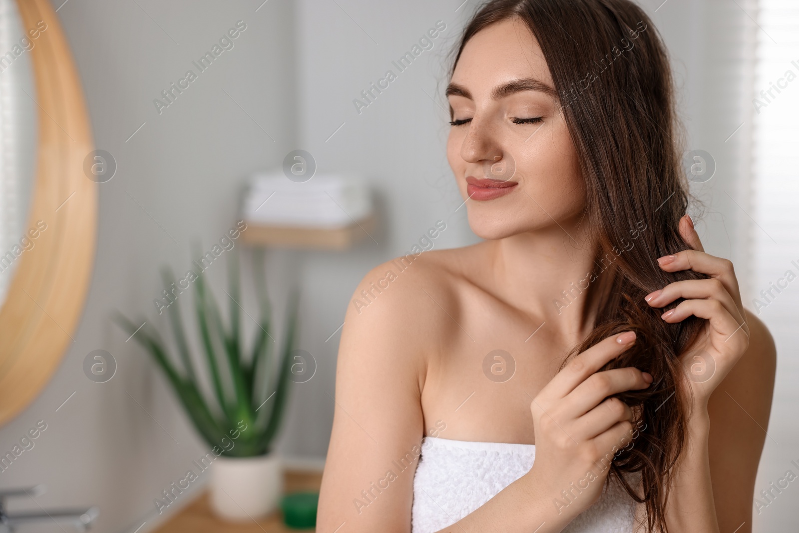 Photo of Young woman applying cosmetic hair mask in bathroom. Space for text