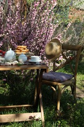 Beautiful spring flowers, freshly baked waffles and ripe strawberries on table served for tea drinking in garden