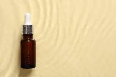 Photo of Bottle of cosmetic serum and water on beige background, top view. Space for text