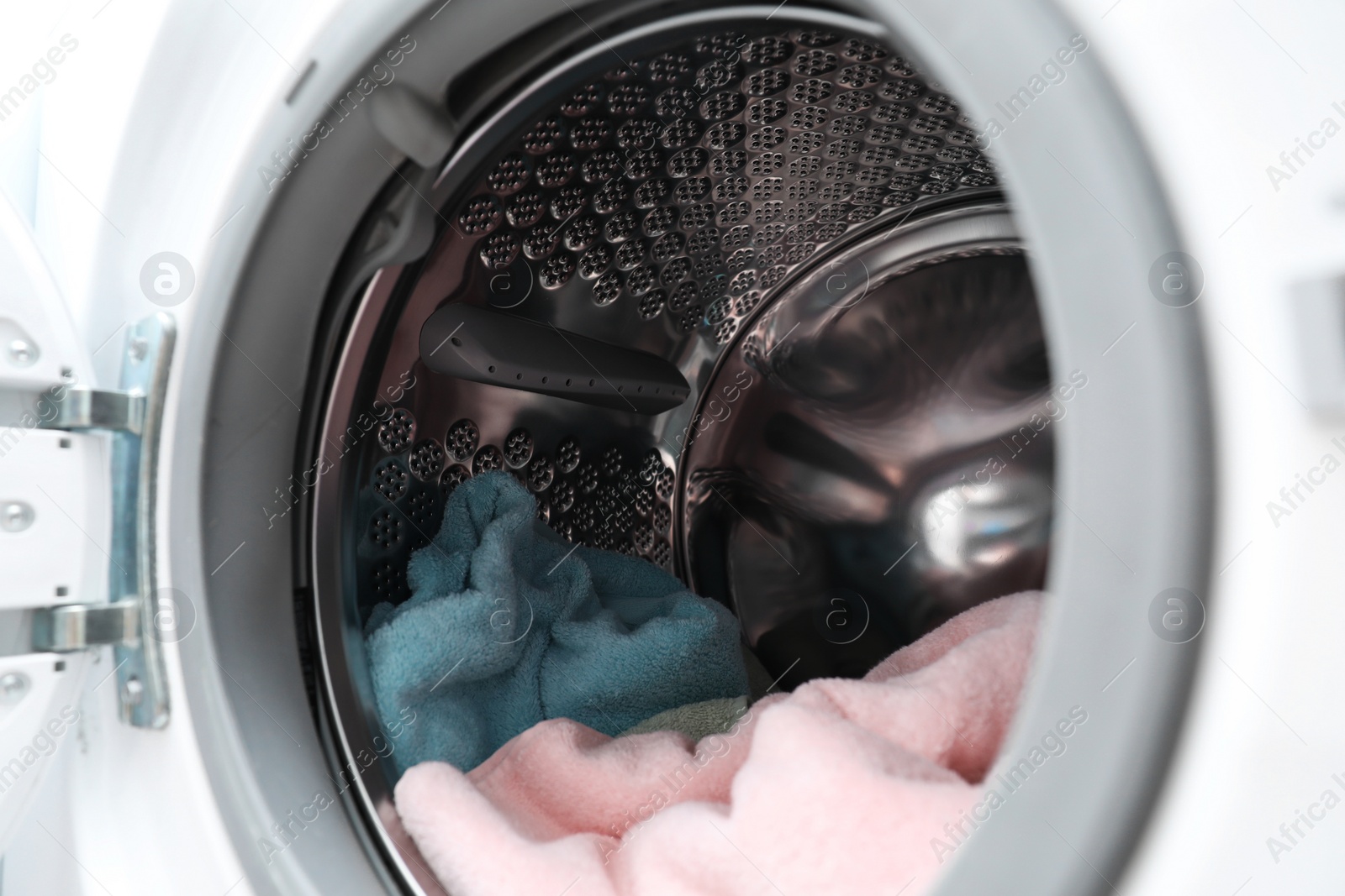 Photo of Modern washing machine drum with laundry, closeup