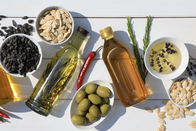 Flat lay composition with different cooking oils and ingredients on white wooden table