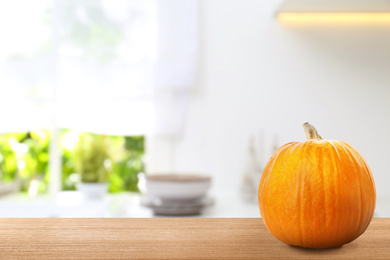 Image of Fresh pumpkin on wooden table in kitchen. Space for text