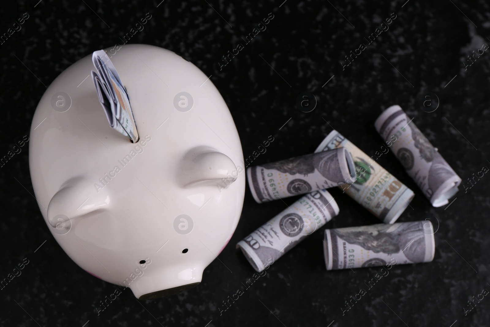 Photo of Financial savings. Piggy bank and dollar banknotes on black textured table, flat lay