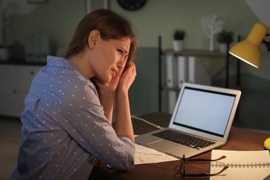 Photo of Overworked young woman with headache in office