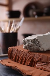 Photo of Clay on dark gray wooden table in workshop, closeup