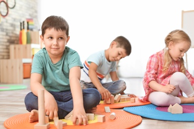 Photo of Cute little children playing with wooden blocks indoors