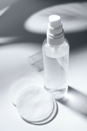 Photo of Bottle of micellar water and cotton pads on white table