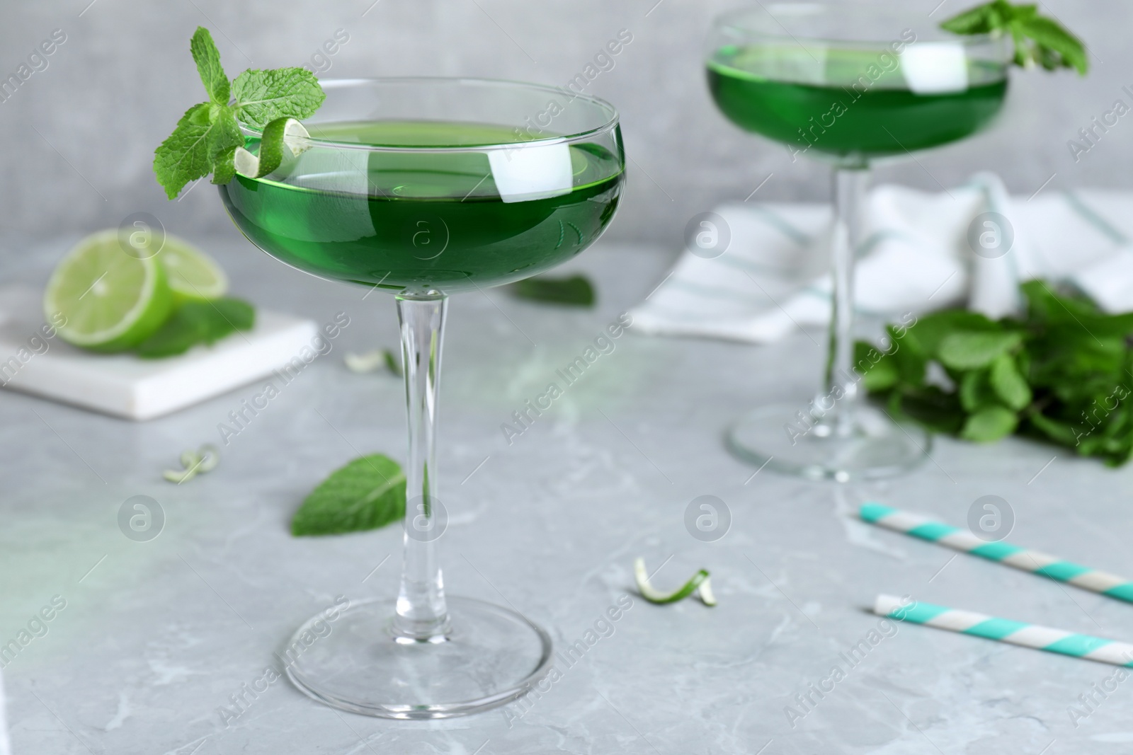 Photo of Delicious mint liqueur with green leaves on light grey marble table. Space for text