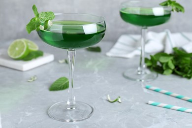 Photo of Delicious mint liqueur with green leaves on light grey marble table. Space for text