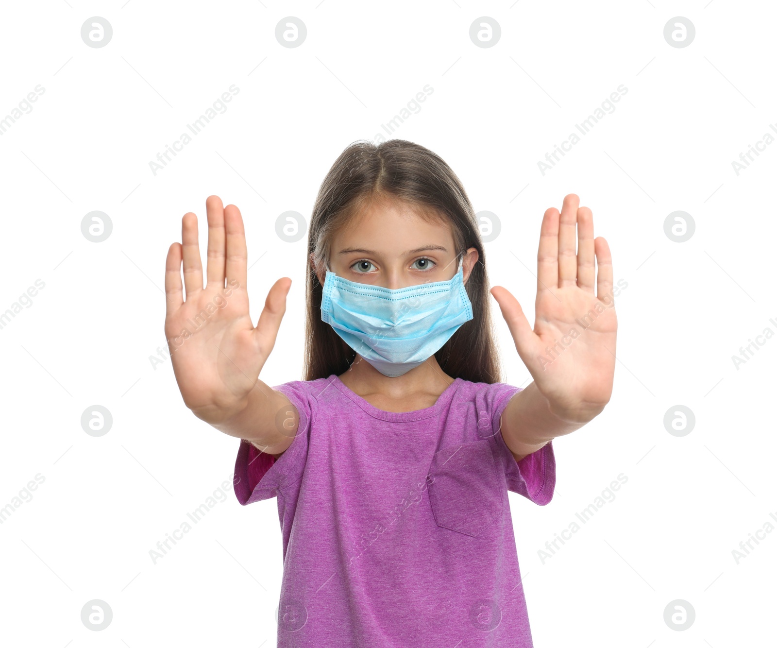 Photo of Little girl in protective mask showing stop gesture on white background. Prevent spreading of coronavirus