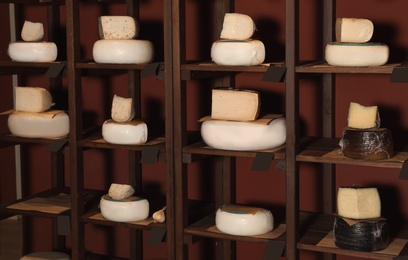 Photo of Different types of delicious cheeses on rack in store