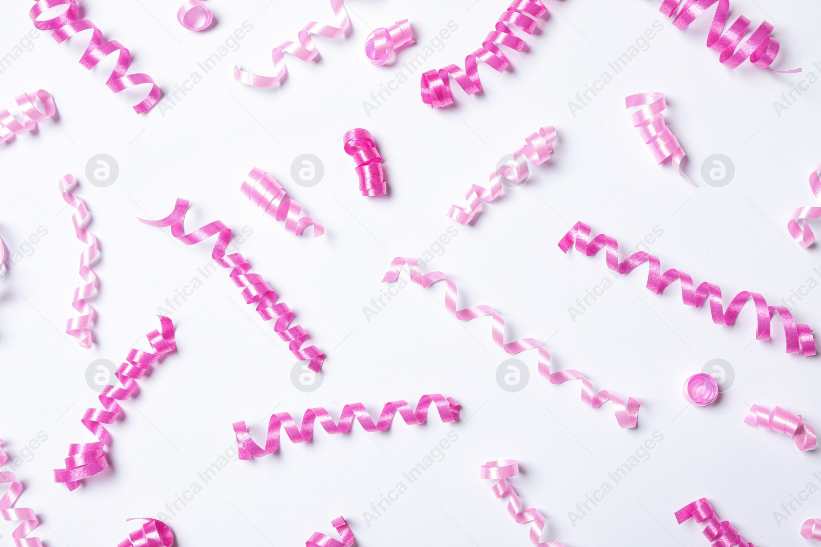 Photo of Pink serpentine streamers on white background, top view