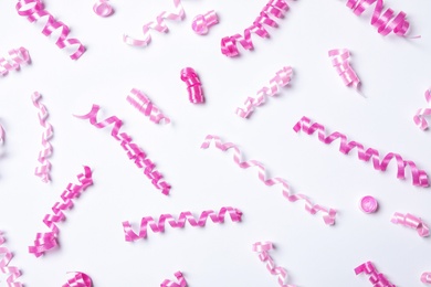 Photo of Pink serpentine streamers on white background, top view