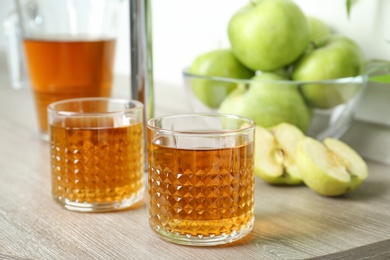 Glasses of apple juice on wooden table