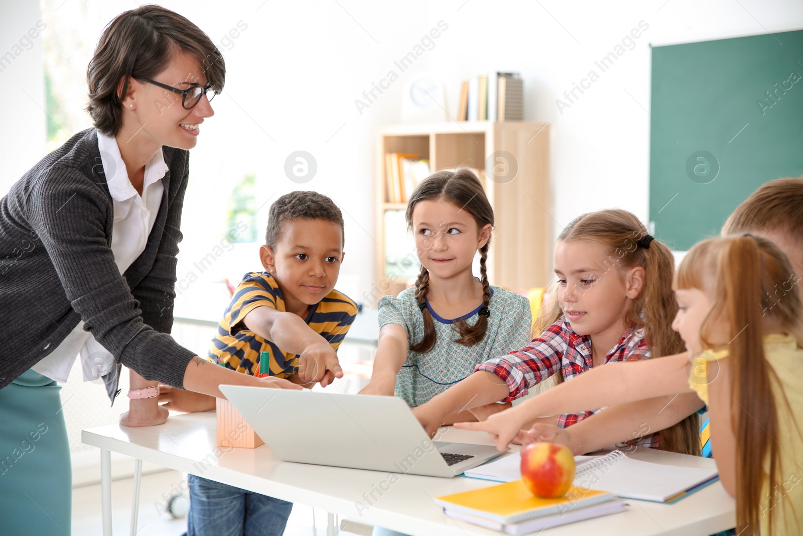 Photo of Female teacher helping children with assignment at school