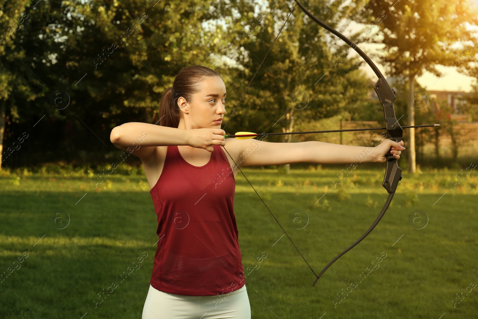 Photo of Woman with bow and arrow practicing archery in park