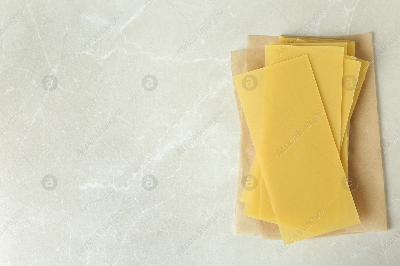 Photo of Uncooked lasagna sheets on marble table, top view. Space for text