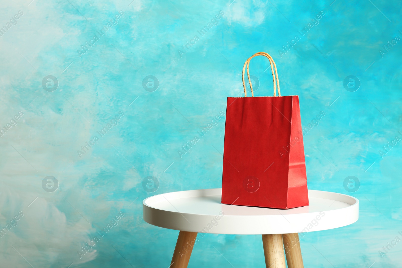 Photo of Mockup of paper shopping bag on table against color background