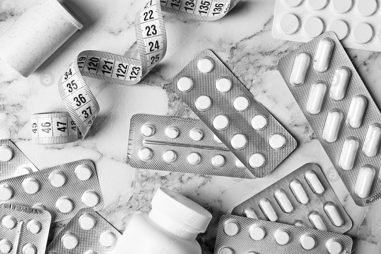 Photo of Flat lay composition with weight loss pills and measuring tape on marble background