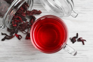 Delicious hibiscus tea and dry flowers on white wooden table, flat lay