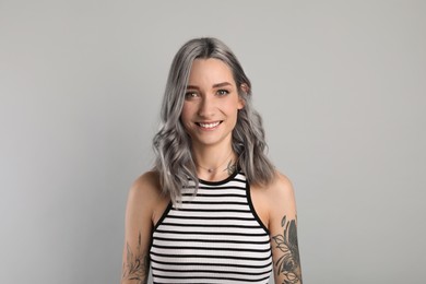 Image of Portrait of smiling woman with ash hair color on light grey background