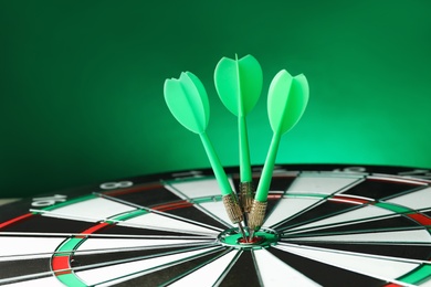 Photo of Arrows hitting target on dart board against green background