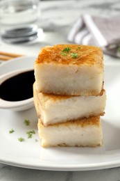 Photo of Plate with turnip cake on white marble table, closeup