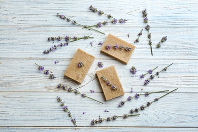 Flat lay composition of handmade soap bars with lavender flowers on white wooden background