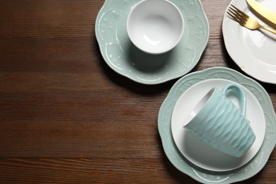 Photo of Beautiful ceramic dishware, cup and cutlery on wooden table, flat lay. Space for text