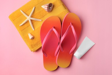 Sunscreen and beach accessories on pink background, flat lay