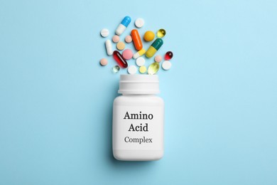 Plastic bottle with Amino Acid Complex and pills on light blue background, flat lay