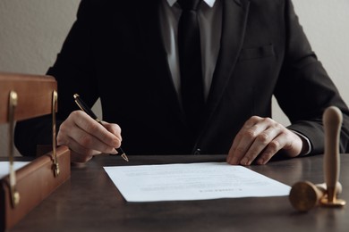 Photo of Male notary signing document at table, closeup