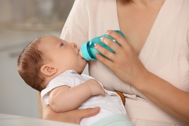 Photo of Mother feeding her cute child with infant formula indoors