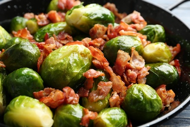 Photo of Tasty roasted Brussels sprouts with bacon in frying pan, closeup