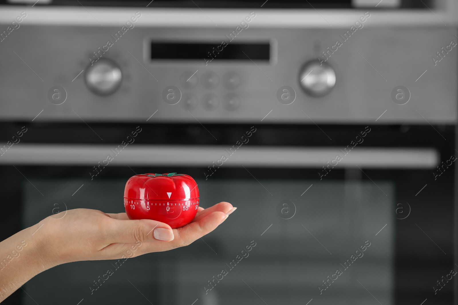 Photo of Woman holding kitchen timer in shape of tomato near oven, closeup. Space for text