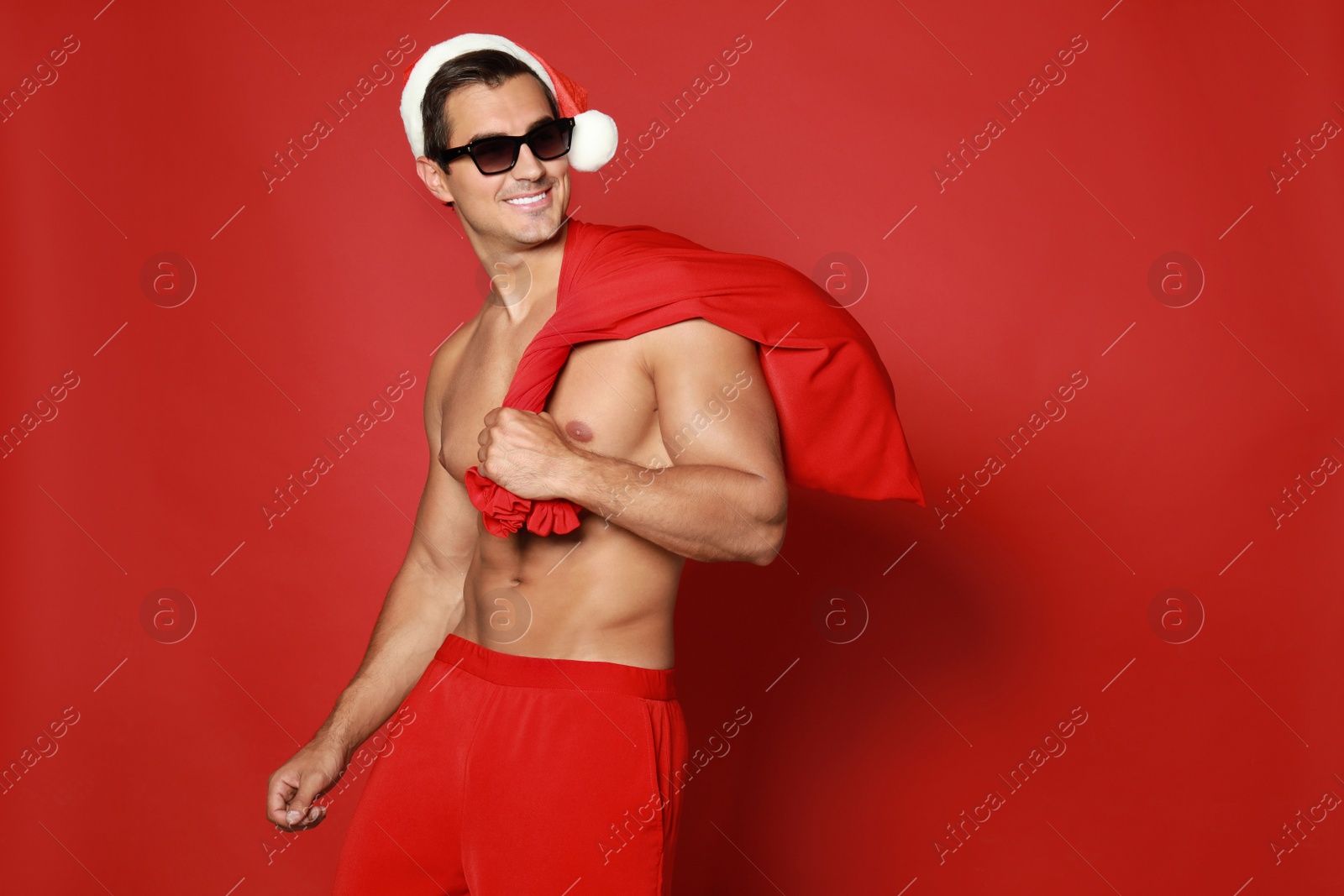 Photo of Sexy shirtless Santa Claus on red background, space for text