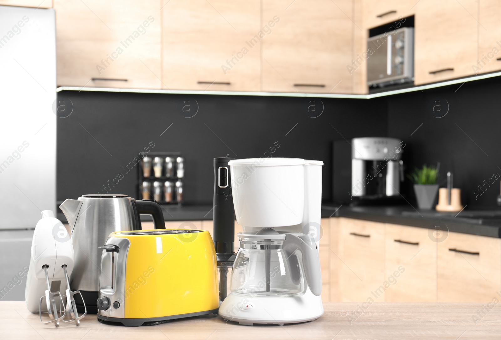 Photo of Modern domestic appliances on wooden table in kitchen. Space for text