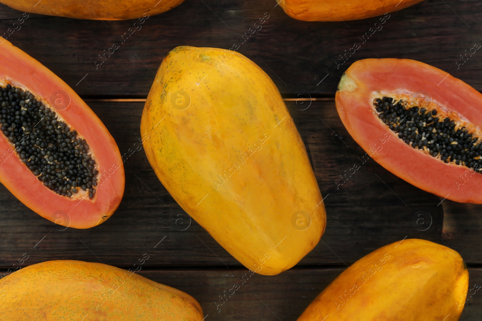 Photo of Fresh ripe cut and whole papaya fruits on wooden table, flat lay