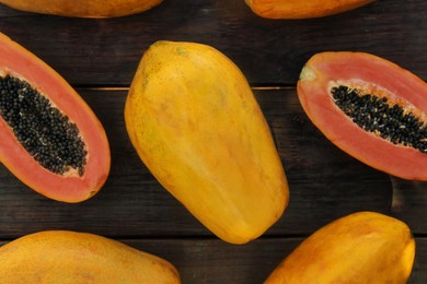 Fresh ripe cut and whole papaya fruits on wooden table, flat lay