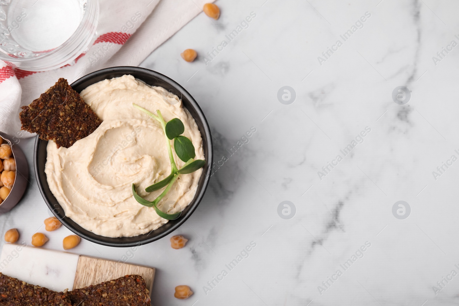 Photo of Delicious hummus with crispbread served on white marble table, flat lay. Space for text