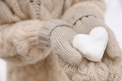 Photo of Woman holding heart made of snow, closeup view