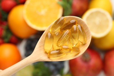 Photo of Vitamin pills in spoon over fresh fruits, top view