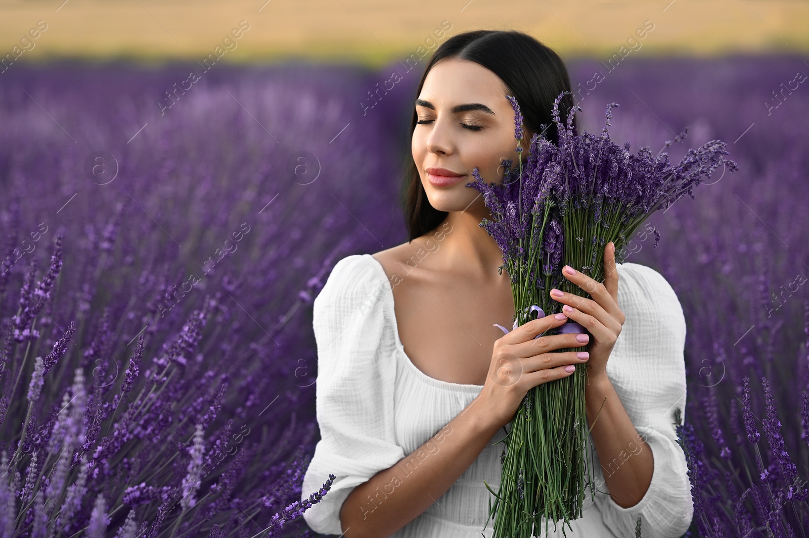 Photo of Beautiful young woman with bouquet in lavender field