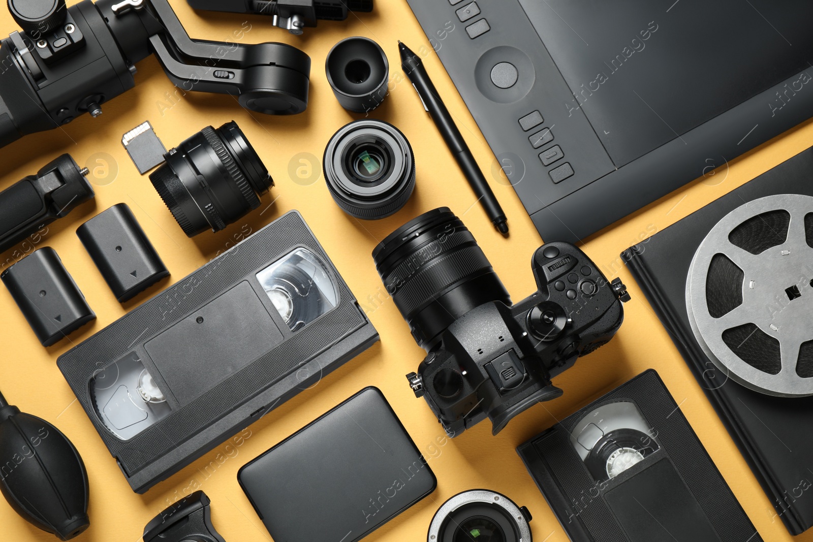 Photo of Flat lay composition with camera and video production equipment on yellow background