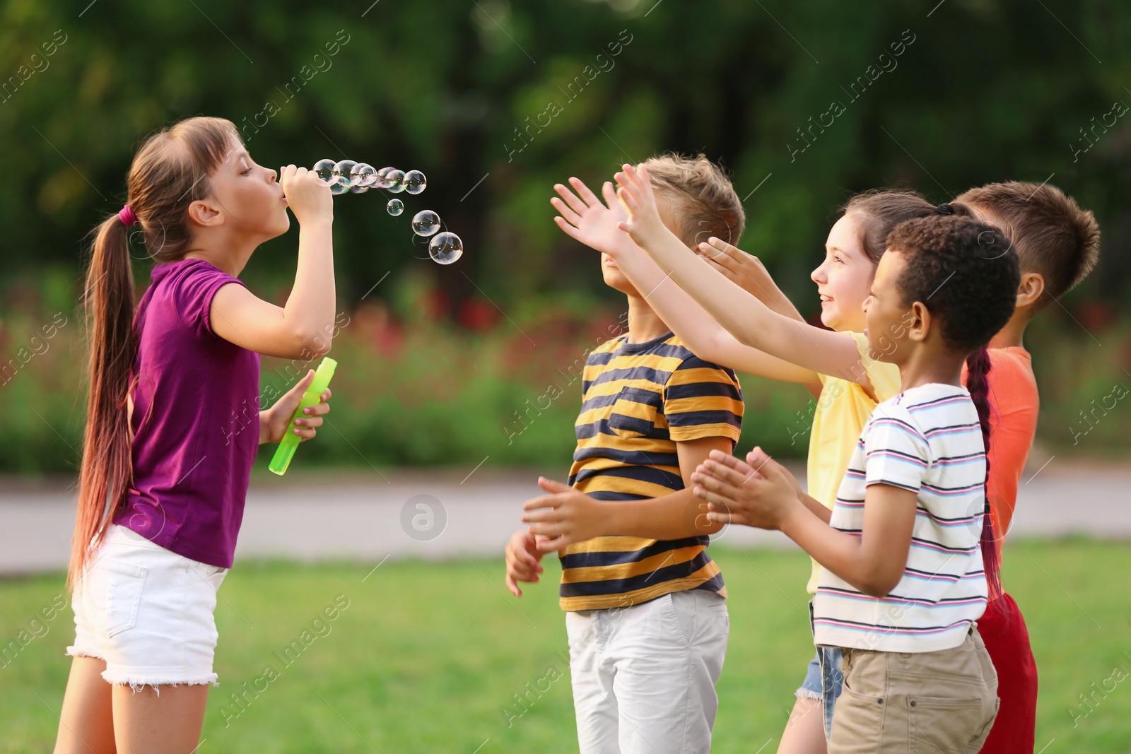 Photo of Cute little children playing with soap bubbles in park