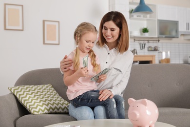 Mother and daughter counting money on sofa indoors